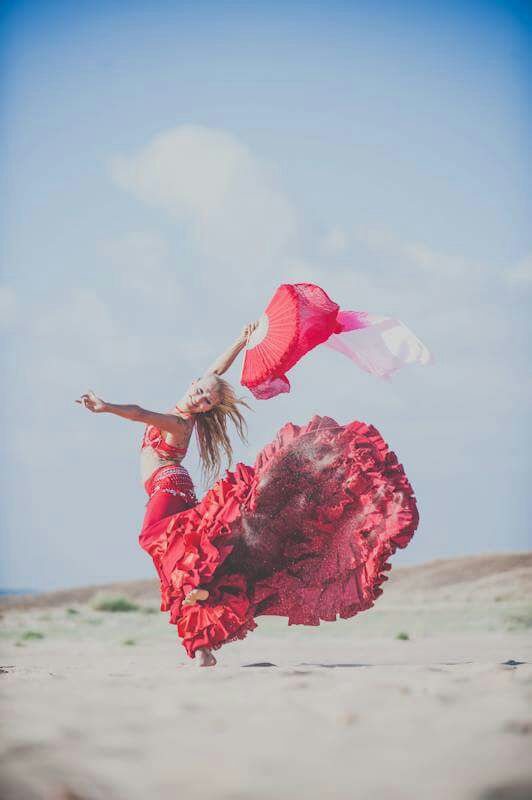 Woman dancing flamenco in a red dress on the beach