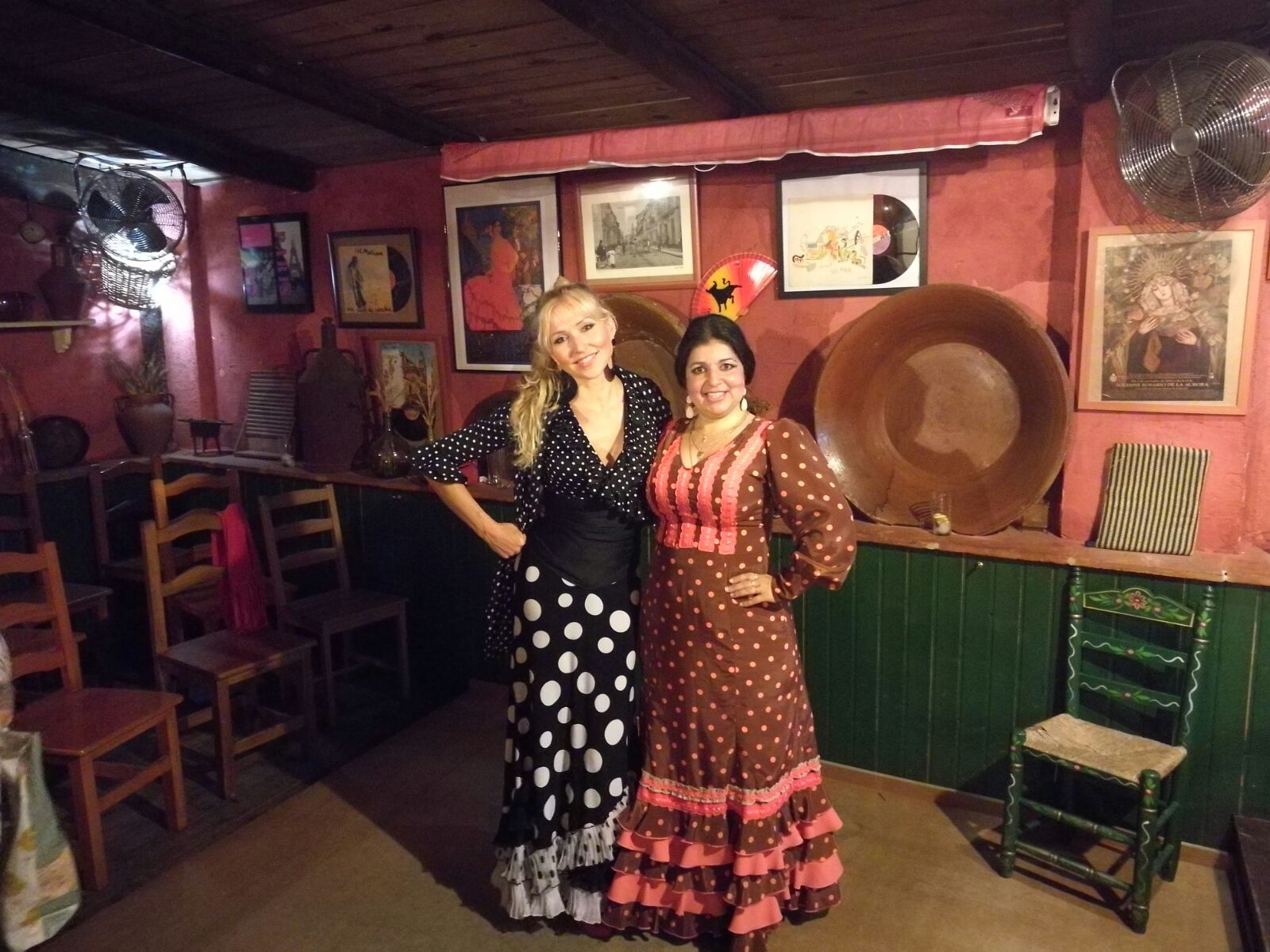 2 women wearing flamenco dresses in a traditional tablao in Seville, Spain